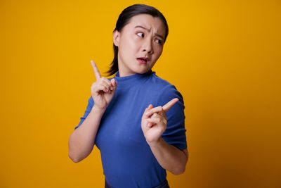 Boy looking away while standing against yellow background