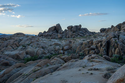 Rock formations on desert land against sky during sunset