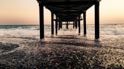 Silhouette pier on beach against sky during sunset