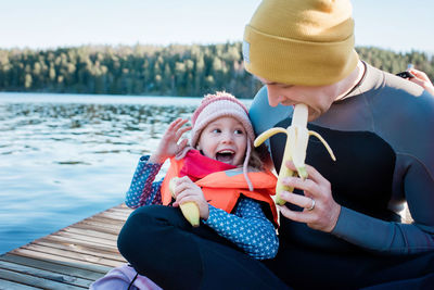 Father and daughter eating fruit at the beach on vacation in winter