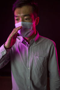 Portrait of young man standing against black background