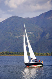 Sailboat sailing on sea against mountains