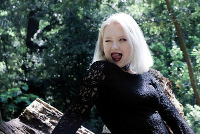 Woman winking and sticking out tongue in forest