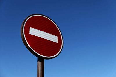 Low angle view of do not enter sign against clear blue sky