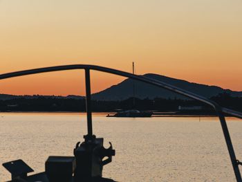 Silhouette bridge by sea against sky during sunset