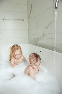 Little brother and sister bathing in a foam bath