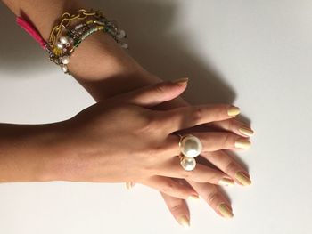 Cropped image of woman wearing rings and bracelet in hands against white background