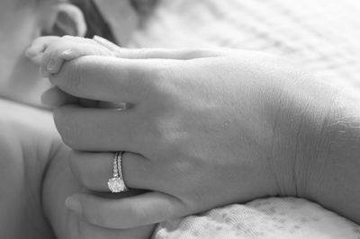 Close-up of baby hand holding mother finger on bed at home