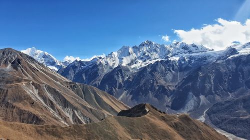 Scenic view of snowcapped mountains against blue sky