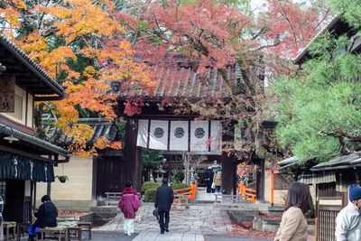 People walking on street amidst trees during autumn