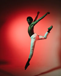 Full length of young woman dancing against white background