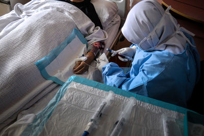 High angle view of doctor injecting syringe to patient at hospital