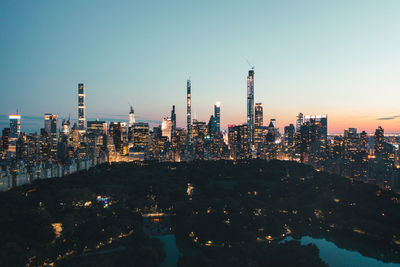 Illuminated modern buildings in city against sky