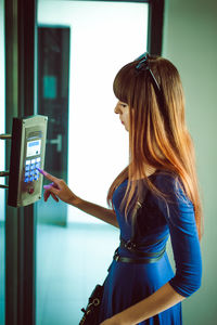 Side view of young woman using elevator buttons