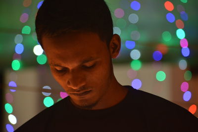 Close-up of young men standing against illuminated lights at night