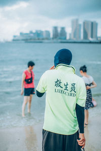 Rear view of people standing on beach