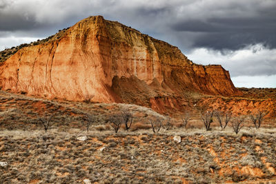 Scenic view of red cliffs against grey sky