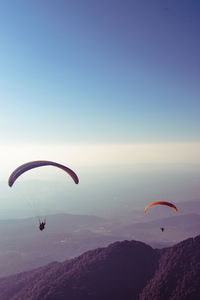 People paragliding over mountain against sky