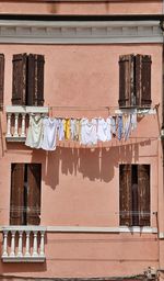 Orange house with laundry hanging, laundry lines nailed to the wall, brown wooden shutters