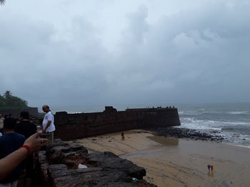 People standing on beach against sky