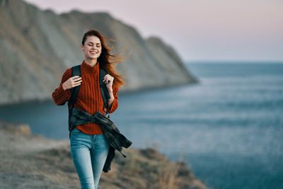 Full length of smiling young woman on beach