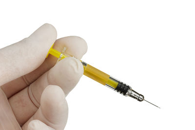 Close-up of hand holding cigarette against white background