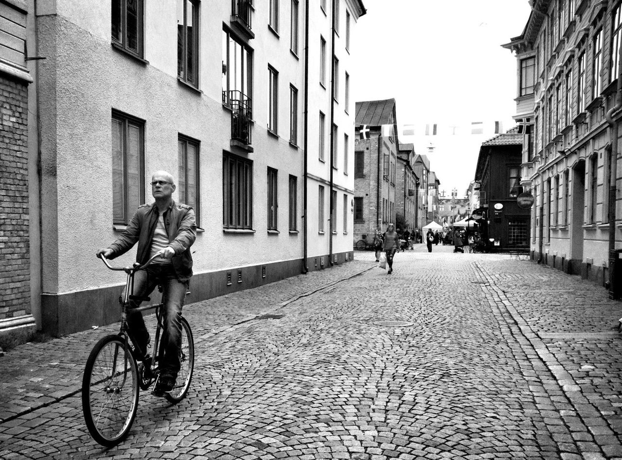 bicycle, building exterior, architecture, built structure, full length, transportation, lifestyles, mode of transport, street, riding, city, men, land vehicle, leisure activity, walking, cobblestone, casual clothing, city life