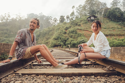 Portrait of smiling young couple sitting against trees