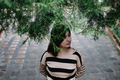 Young woman standing against tree