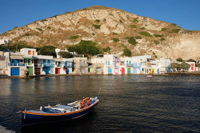 Boats moored on sea by buildings against sky