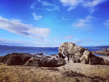 Rock formations on shore against blue sky