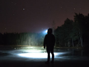 Rear view of silhouette man on road at night