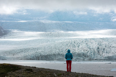 Tourist admiring the icebergs drifting in the water in fjallsarlon glacier lagoon, iceland