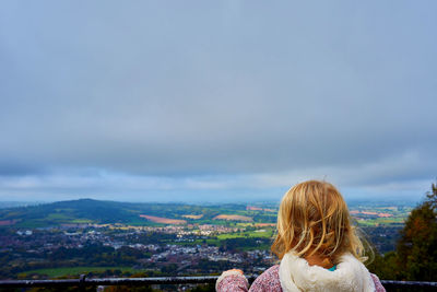 Rear view of woman looking at cityscape against sky