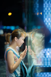 Side view of smiling woman looking through window