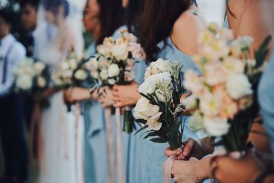 Midsection of women holding bouquet during wedding ceremony