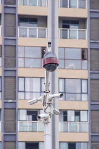 Low angle view of electric lamp against building