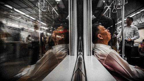 Reflection of people on glass window of train