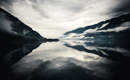 Reflection of clouds in river amidst mountains at dusk