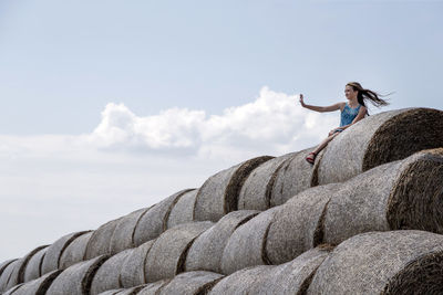 Low angle view of woman standing on rock against sky