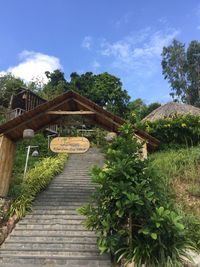 Footpath amidst trees and building against sky