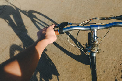 Cropped hand of person riding bicycle on road