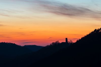 Scenic view of silhouette mountains against orange sky