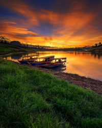 Boats moored in lake against sky during sunset