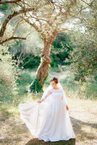 Full length of bride standing in forest