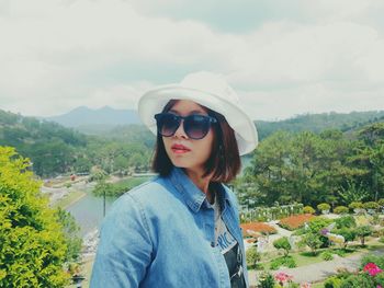 Young woman wearing sun hat while standing on mountain against sky