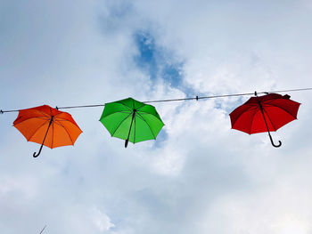 Low angle view of umbrellas hanging against sky