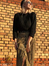 Young woman standing against brick wall