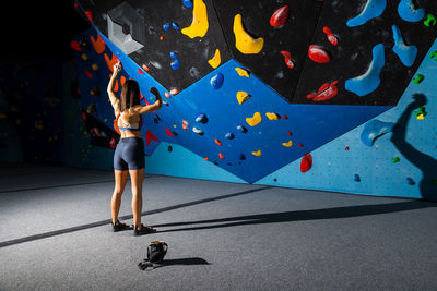 Young woman preparing the ascent towards an indoor climbing wall