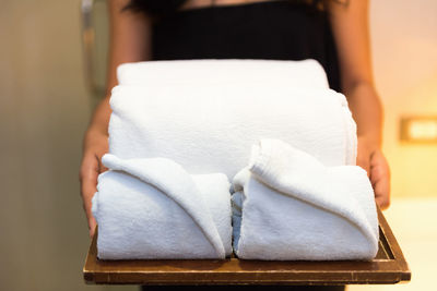 Midsection of woman holding towels in tray at spa